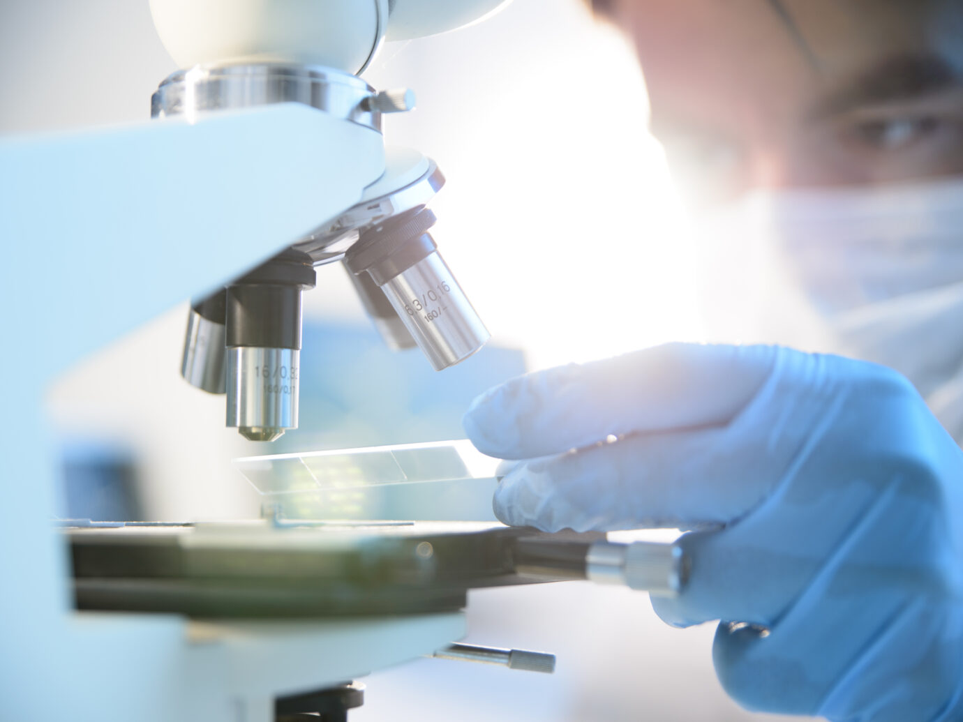 A scientist placing a slide under a microscope