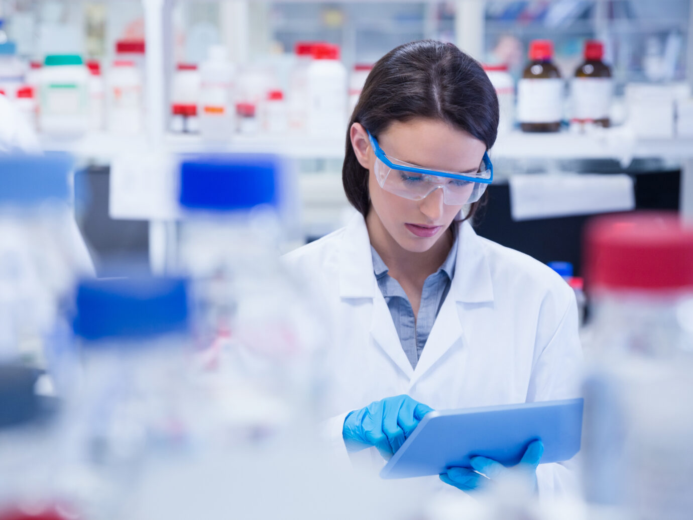 Chemist wearing safety glasses and using tablet pc